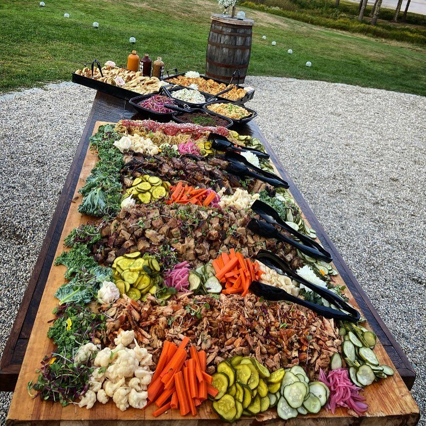 BBQ wedding buffet with pulled meats and fresh vegetables on a wooden table.