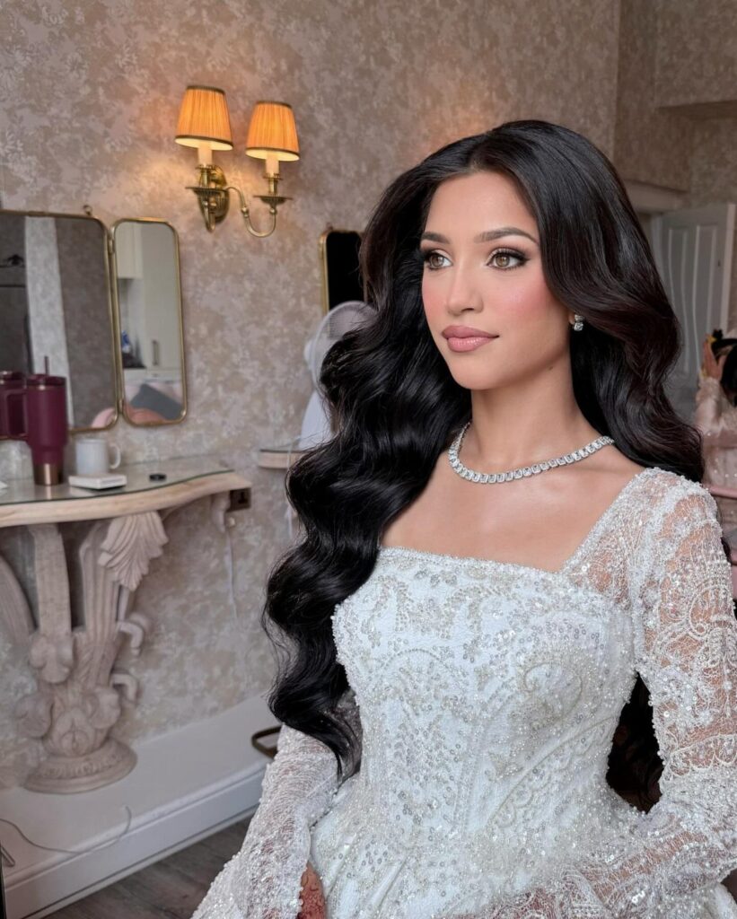 Woman with long dark wavy hair wearing a white lace bridal gown