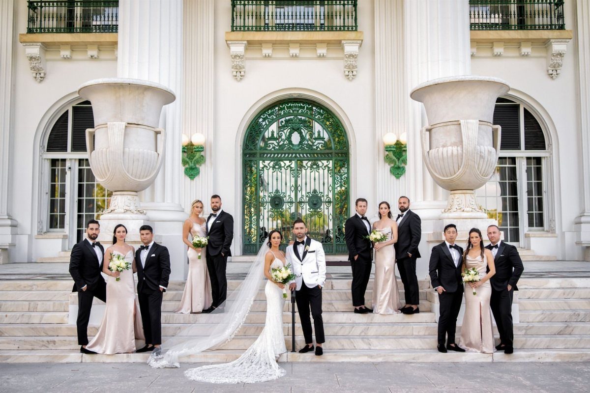 Bride and groom centered on steps surrounded by their bridesmaids and groomsmen.