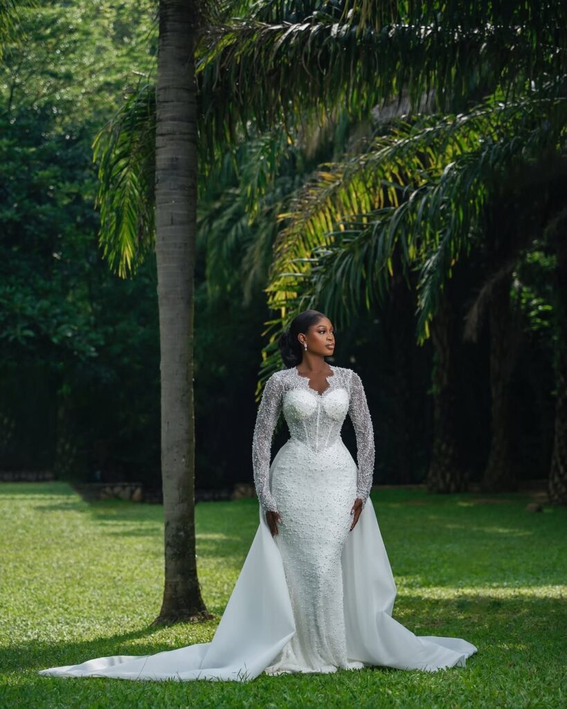 Bride in a white lace wedding gown posing in a tropical garden setting