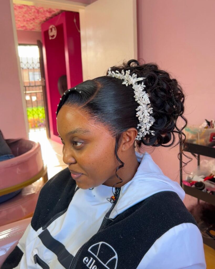Woman with a curly updo and silver floral hair accessory in a room.