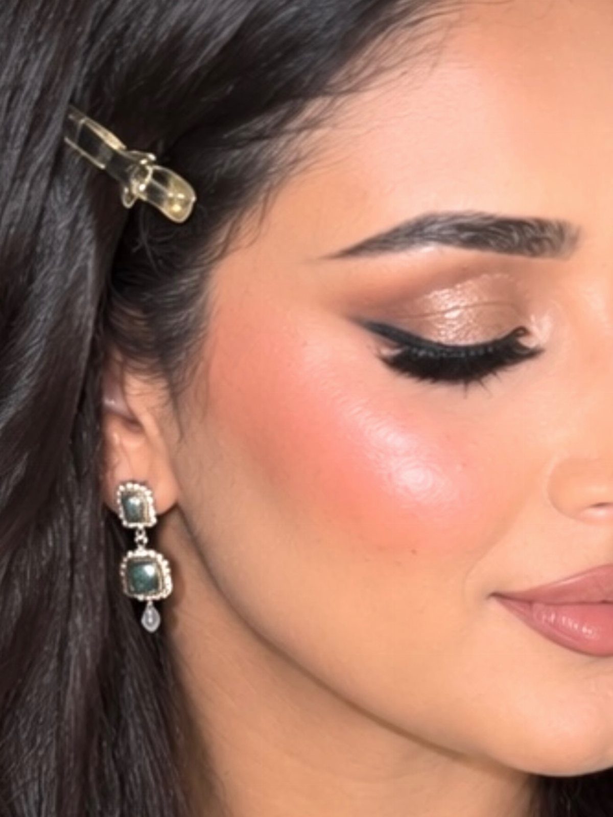 Woman with glamorous wedding makeup, gold eyeshadow, winged liner, and mauve lipstick.
