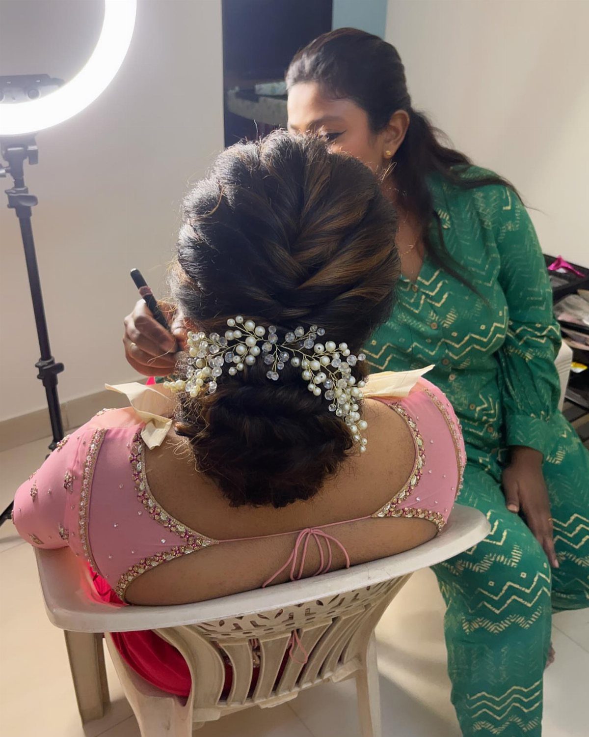 Woman with a voluminous bridal updo and pearl hair accessory being styled.