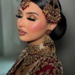 Woman with traditional Indian bridal makeup and gold jewelry wearing a red embroidered outfit