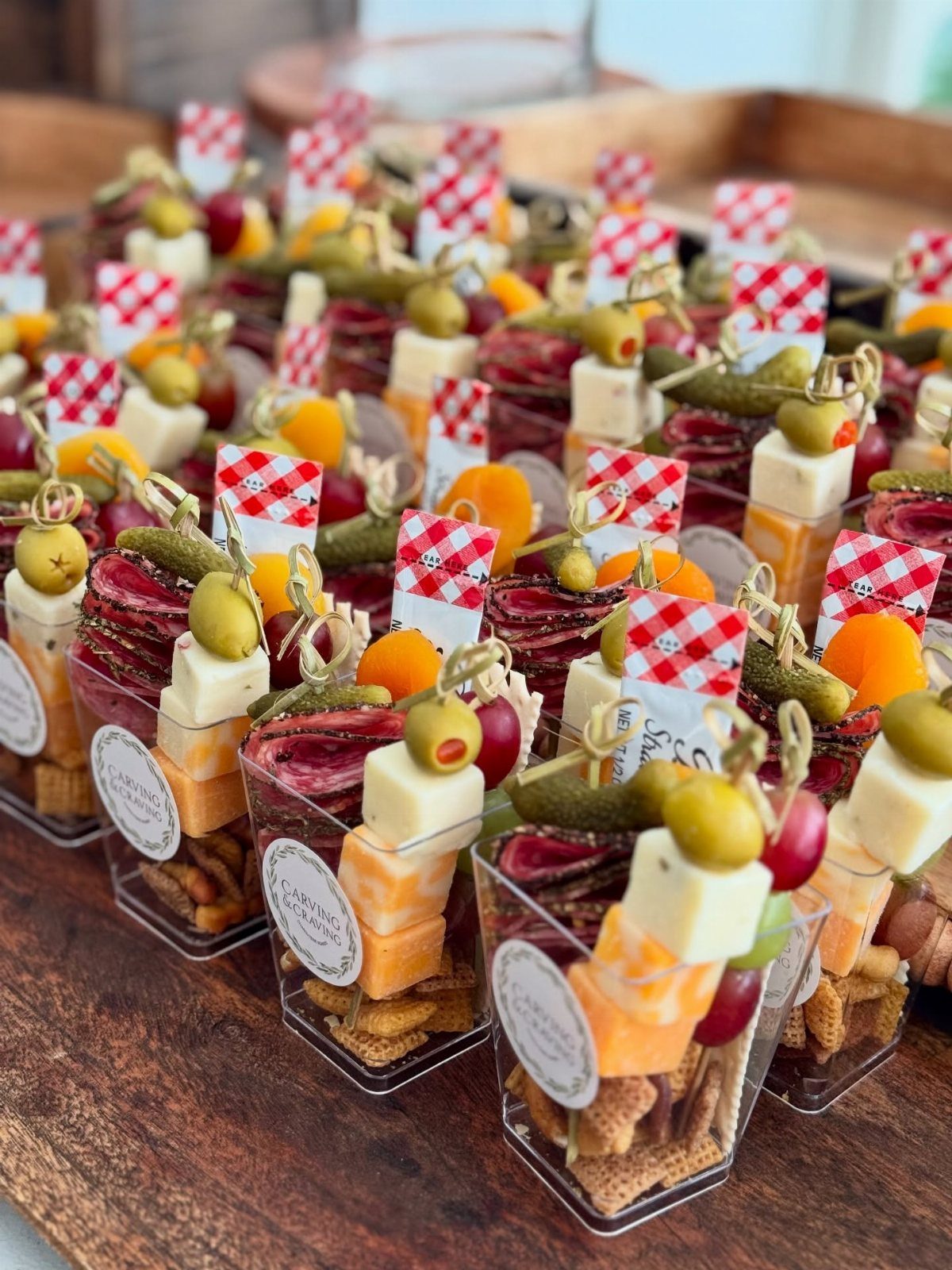 Appetizer skewers with cheese, salami, and olives in small plastic cups on crackers.