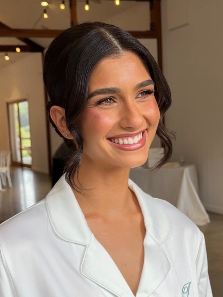 Smiling woman with romantic wedding makeup and an elegant dark hair updo.