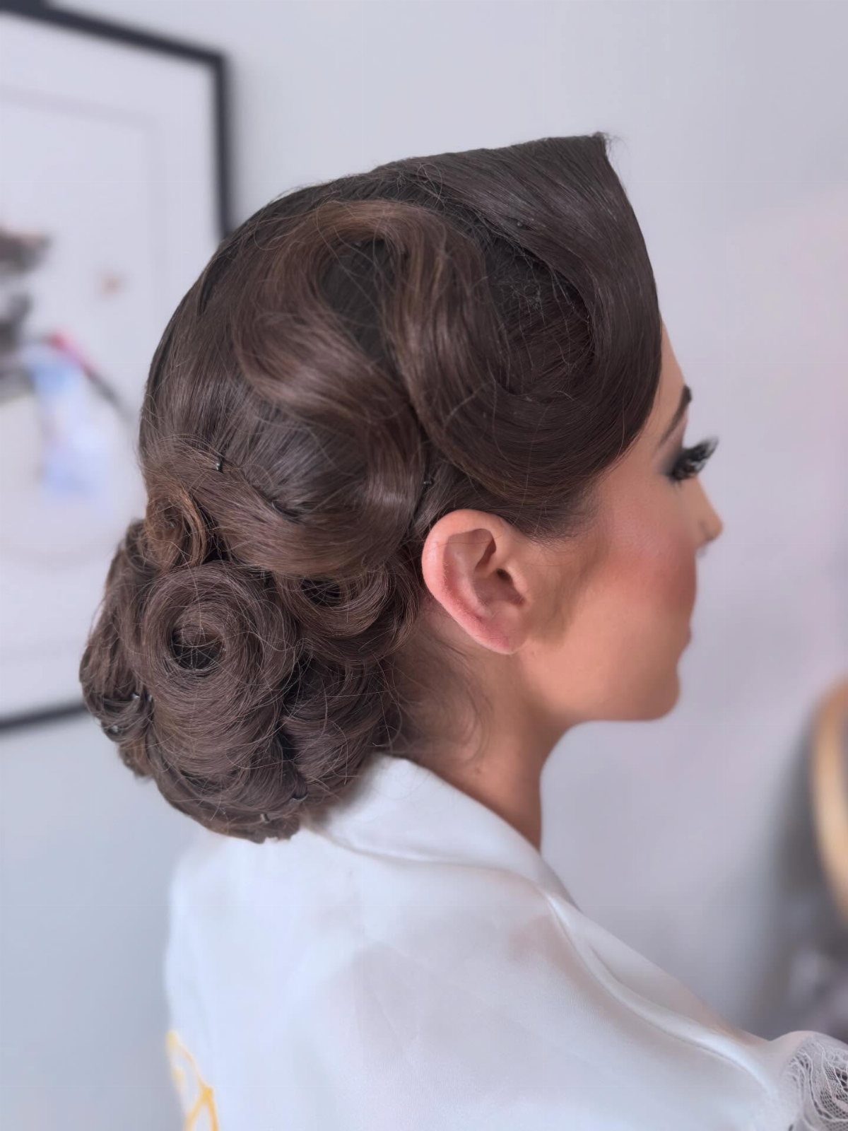 Woman with brown hair in a vintage low bun and structured waves.