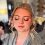 Woman with blonde hair wearing a silver robe and shimmering bridal makeup