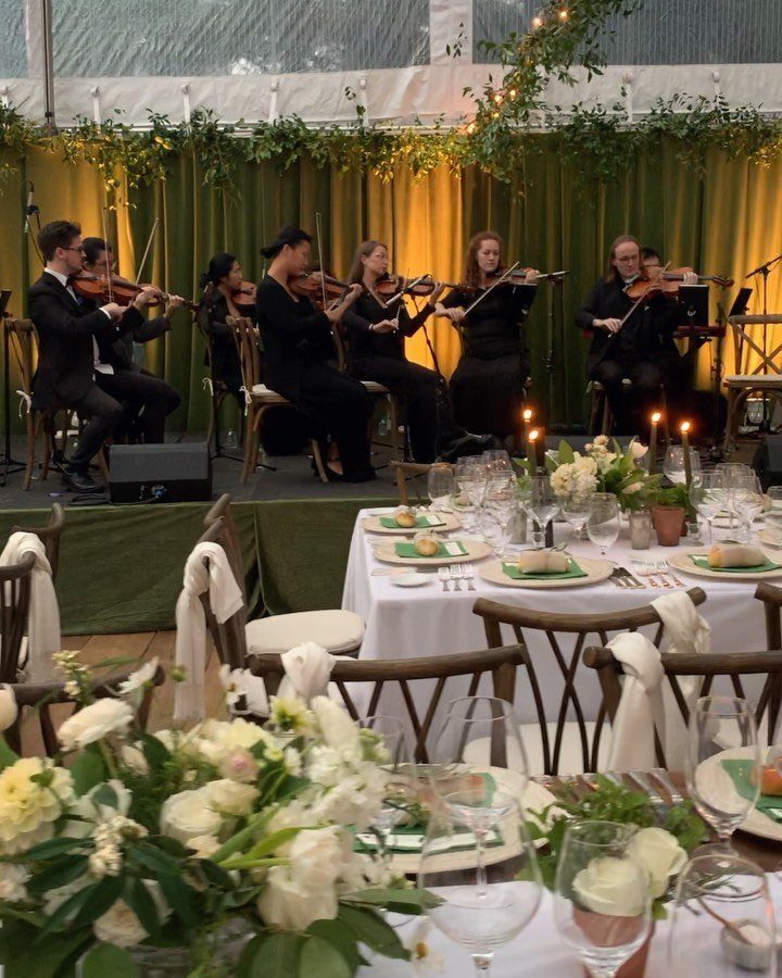 String quartet performing on a stage behind elegantly set wedding dinner tables.