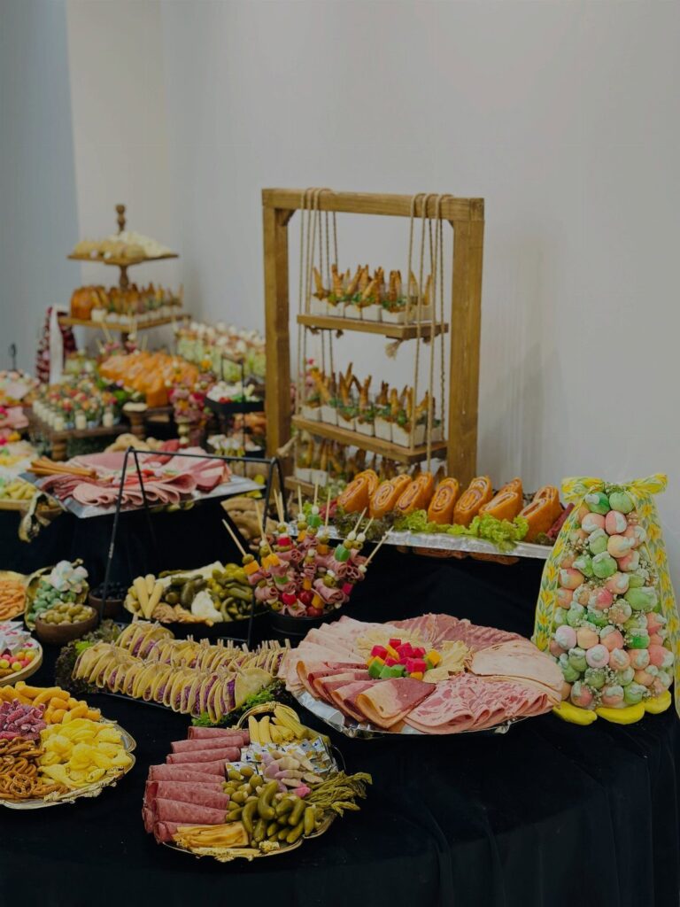 Buffet spread of cured meats, cheeses, and finger foods on a black tablecloth.