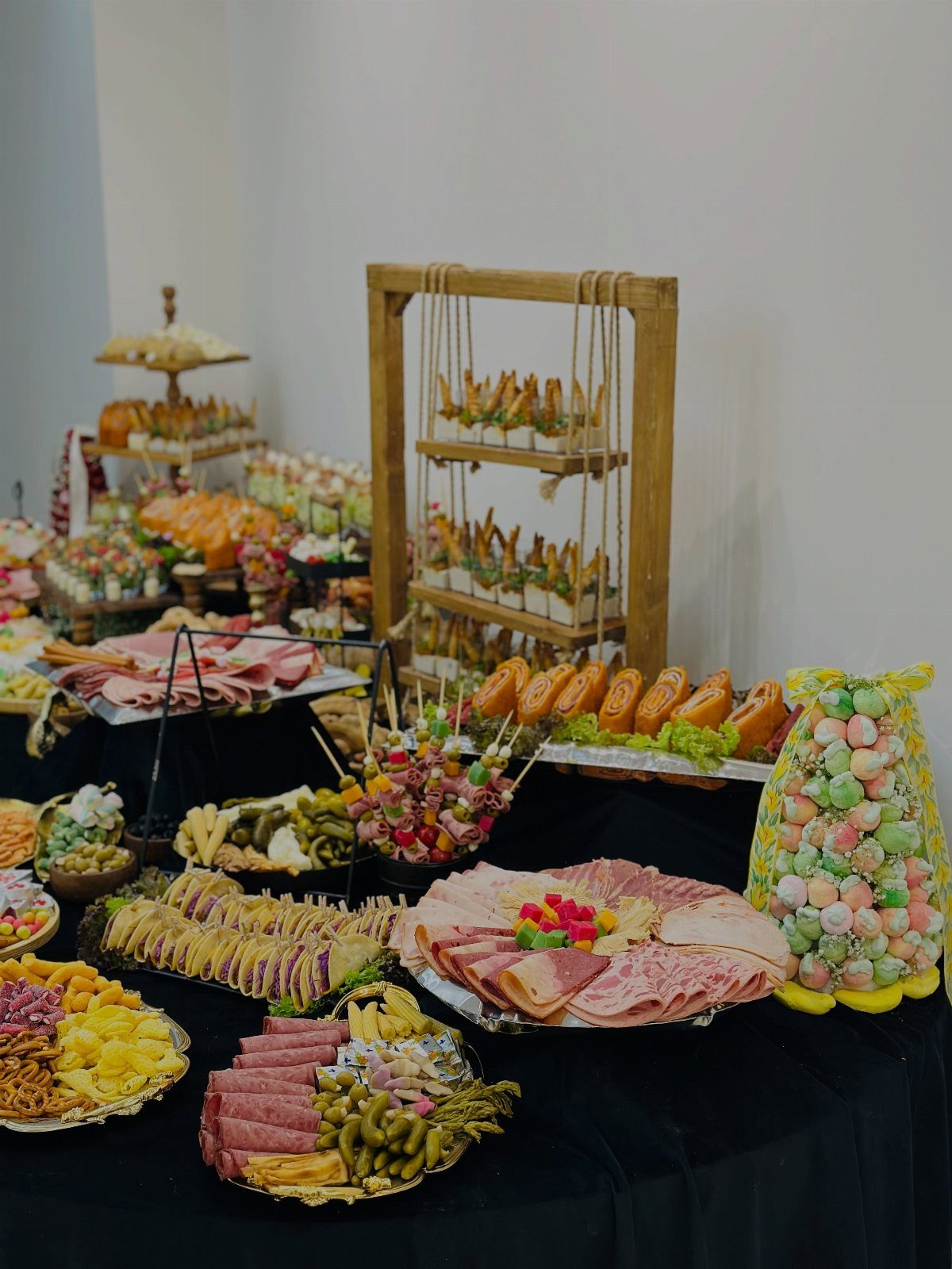 Buffet spread of cured meats, cheeses, and finger foods on a black tablecloth.