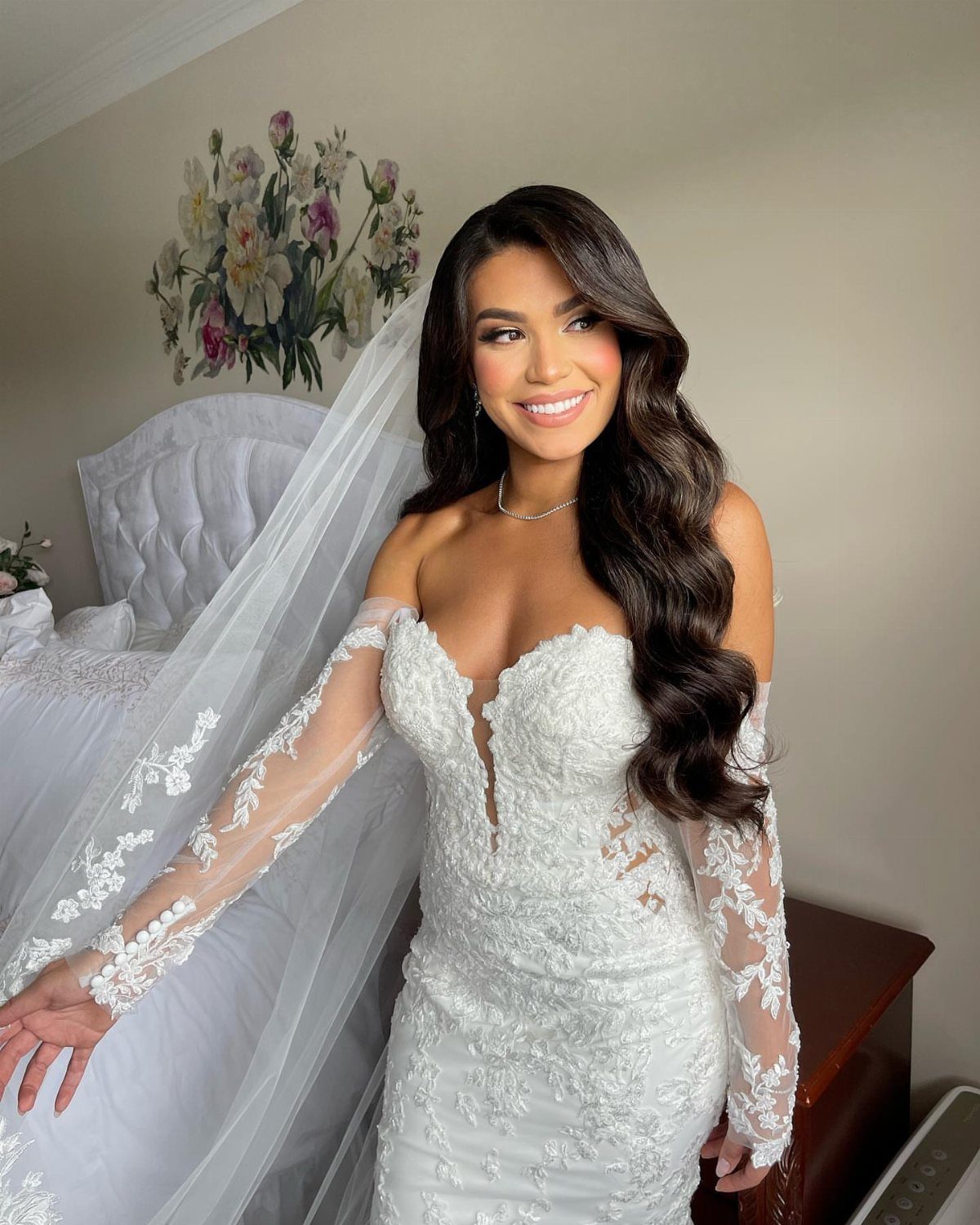 Bride with long dark wavy hair wearing a white lace wedding dress and veil