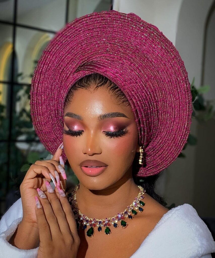 Woman with shimmering pink eyeshadow and magenta headwrap posing for a portrait