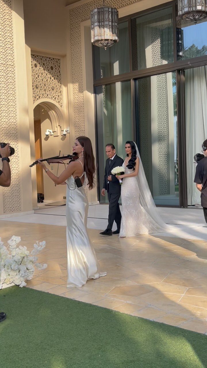 Violinist playing music as a bride is escorted down the aisle outdoors